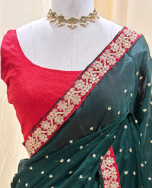 Bottle green satin georgette saree with red border.