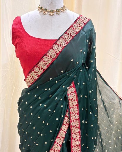 Bottle green satin georgette saree with red border.