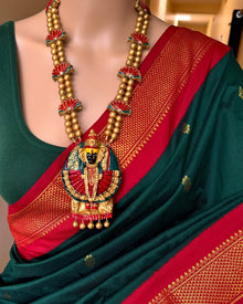 Bottle green cotton silk full butta saree with red border.