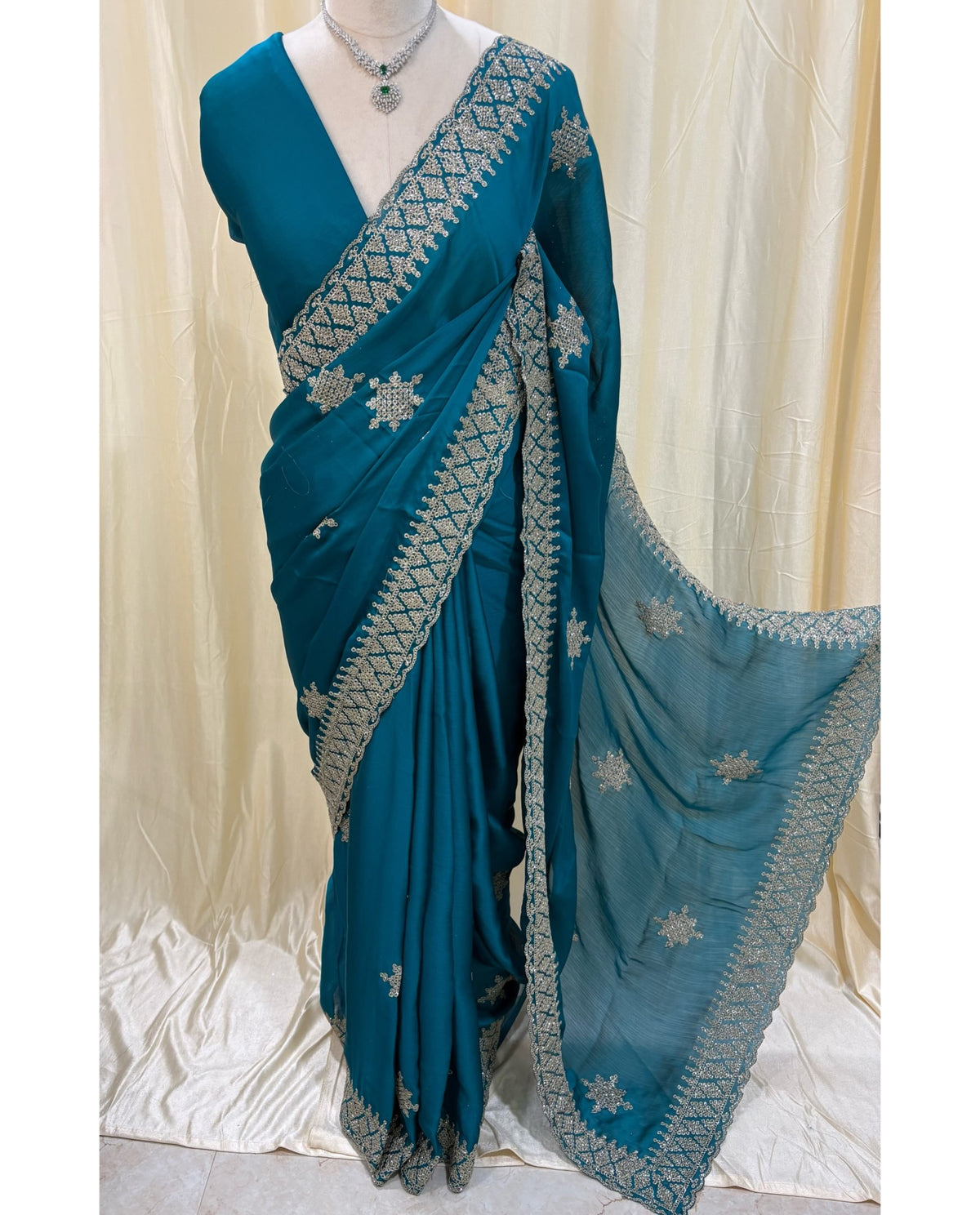 Teal blue georgette saree with golden white embroidery.