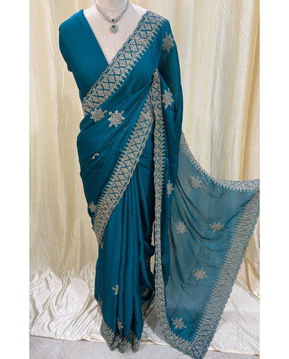 Teal blue georgette saree with golden white embroidery.