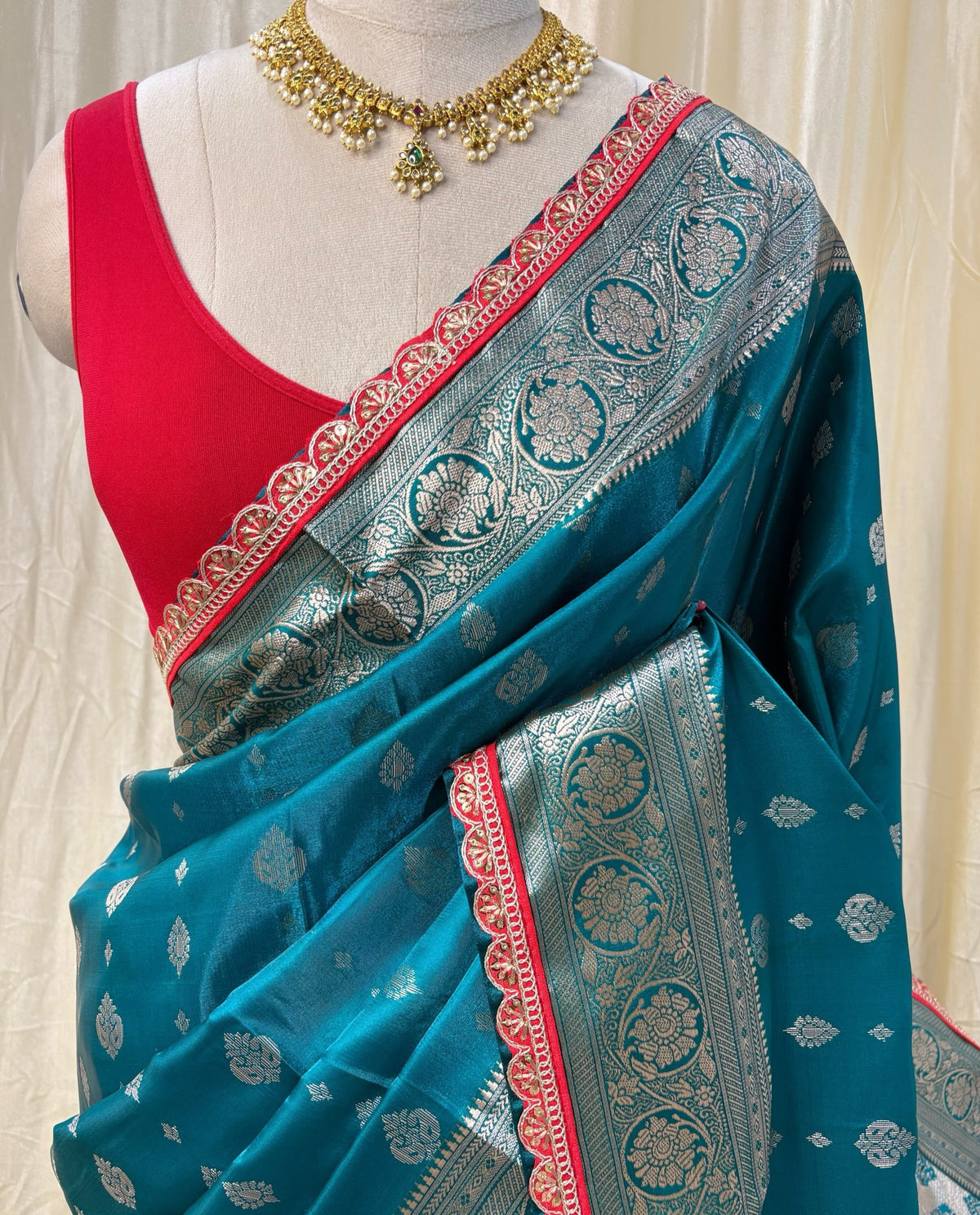 Teal blue satin ailk saree with red lace.