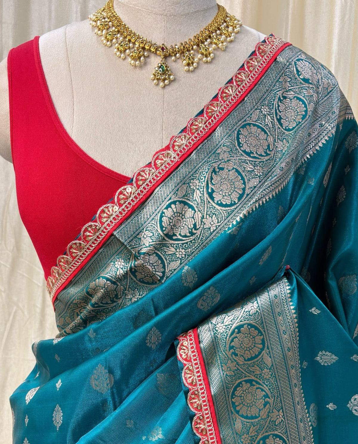 Teal blue satin ailk saree with red lace.
