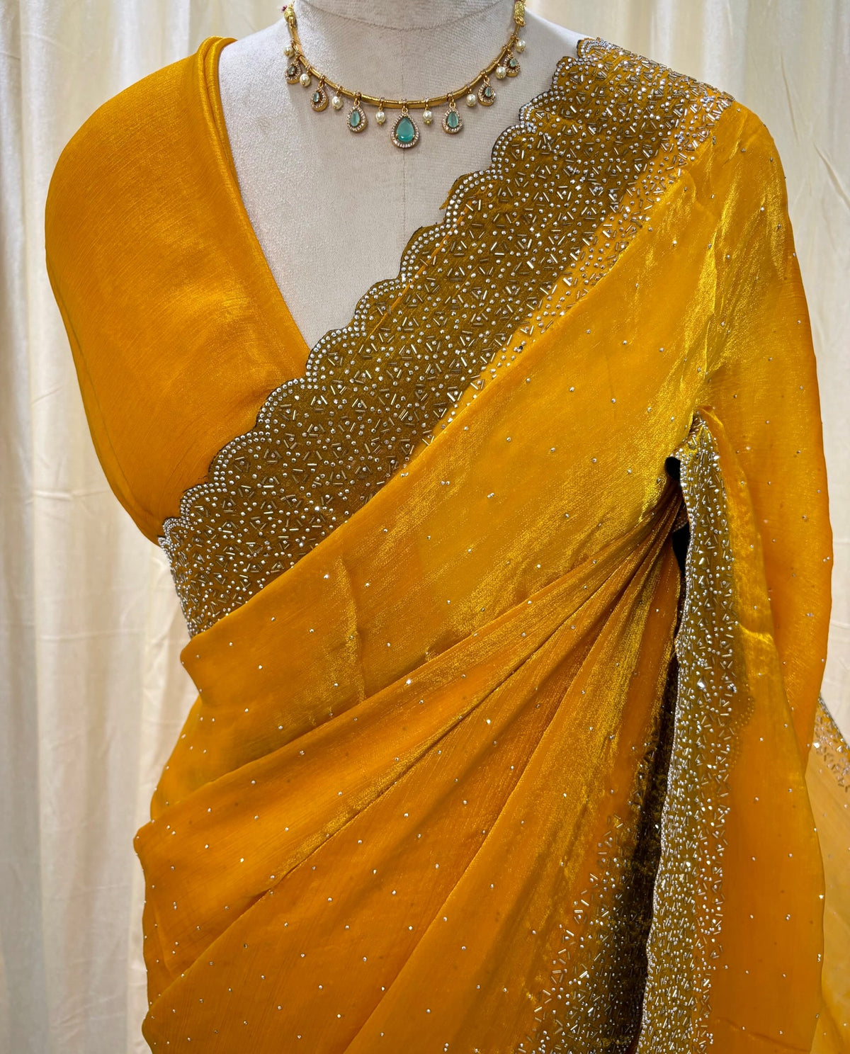 Yellow georgette saree with white stones.