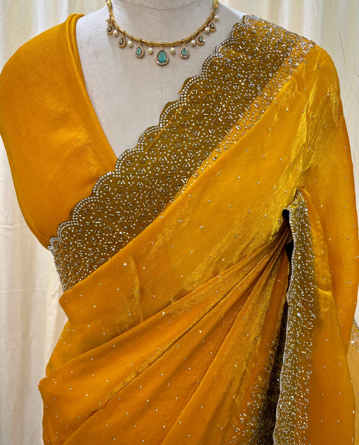 Yellow georgette saree with white stones.